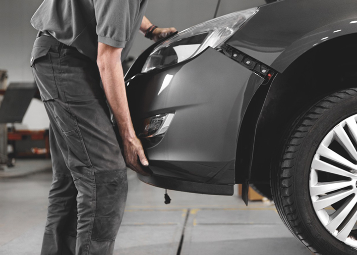 Man putting bumper back on car